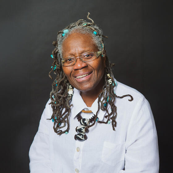 Joyce Joyce in a white shirt smiling and staring into the camera