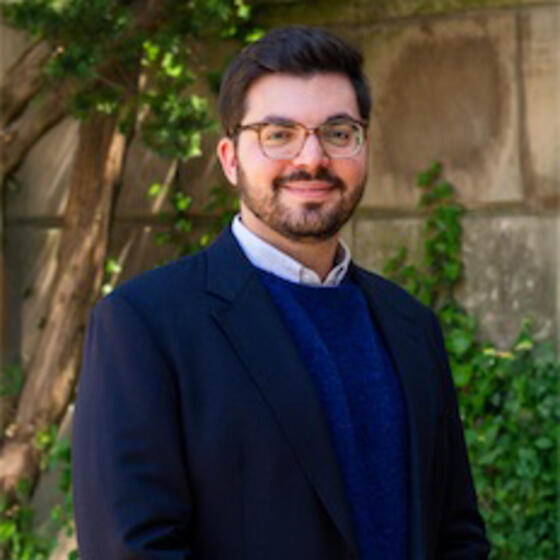 Dan Confalone in a blue suit coat and vest with a white shirt smiling into the camera