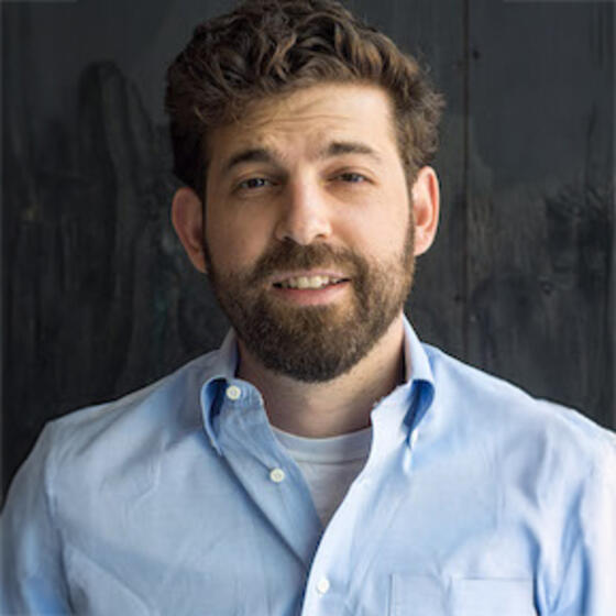Alexander Falbo-Wild in a blue shirt smiling into the camera