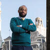 image of student standing in fron the the capitol in a teal sweater with his arms crossed