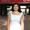 image of Haleigh standing in a white dress smiling in front of the red and white College of Liberal Arts sign