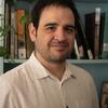 image of Jeronimo Rodriquez standing in front of a teal bookcase with a white dress shirt on