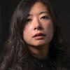 image of Alyssa Songsiridej in a black turtleneck in a black back drop