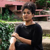 image of Divya Victor in a black dress sitting on brick steps