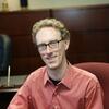 Andrew Karpinski in a red shirt smiling and staring into the camera