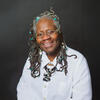 Joyce Joyce in a white shirt smiling and staring into the camera
