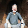 Charles Weitz in India sitting on step outside of a building staring into the camera and smiling