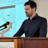Artemy Kalinovsky at a podium in front of a screen teaching