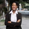 Octavia “Alonge” Clarkson in a white shirt and black suit coat smiling into the camera