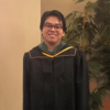 Elijah Bueno in a graduation robe smiling into the camera