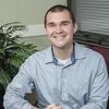 David V. Smith sitting in an office with a blue shirt smiling and staring into the camera