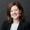 Emma Irvin in a black suit coat smiling into the camera