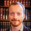 Eugene Chislenko standing in front of a book shelf smiling and staring into the camera