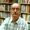 Mohsen Fardmanesh standing in front of a books shelf staring into the camera