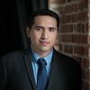 Fernando Fonseca Pacheco Norma Corrales Martin in a black suit and tie staring into the camera