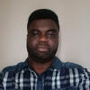 Forster Asare in a navy and white checkered shirt staring into the camera