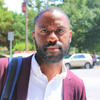 Kevin Anglade outside in a red suit coat and white shirt staring into the camera