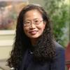 Isabelle Chang in a black suit smiling and staring into the camera