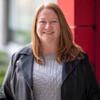 Jamie Fader in a black jacket and gray shirt smiling into the camera