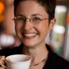 Marian Makins holding a coffee smiling and staring into the camera