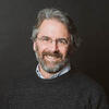 Michael G. Hagen in a black sweater smiling and staring into the camera