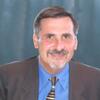 Gary Mucciaroni in a gray suit with a blue shirt on smiling and staring into the camera