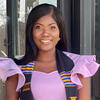 Juanita SSefa in a pink shirt with a graduation stole smiling into the camera