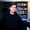 Víctor Pueyo Zoco in front of a book shelf staring into the camera