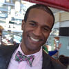 Aaron Smith wearing a pink shirt with a bow tie smiling and staring into the camera