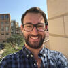 Jason Gravel standing outside with some building behind him staring into the camera and smiling