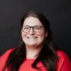 Danielle K. Scherer in a red shirt smiling and staring into the camera