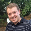 Kevin Doherty outside in a navy shirt with white stripes smiling into the camera