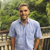 James Kelly standing on deck in front of some trees smiling and staring into the camera