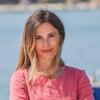 Lara Ostaric in a pink shirt with her arms crossed staring into the camera