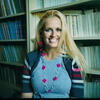Melissa Toomey in a gray shirt with a colorful sweater smiling and staring into the camera