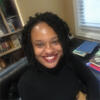 Natalie Léger in her office in a black shirt smiling and staring into the camera