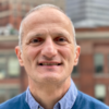 Paul David Toth outside in front of buildings smiling and staring into the camera