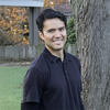 Walter James outside in front of a tree in a black shirt smiling into the camera